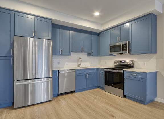 A kitchen with blue cabinets and stainless steel appliances.