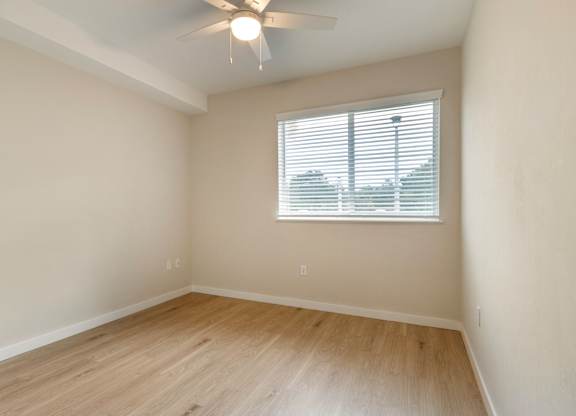 A room with a ceiling fan and a window with blinds.