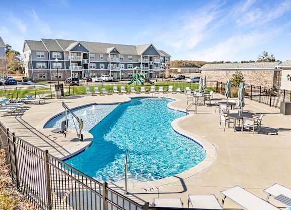 A large swimming pool surrounded by a fence and chairs.