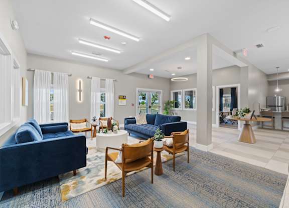 A spacious living room with blue sofas and wooden chairs.