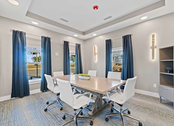 A conference room with a table, chairs, and a window with curtains.