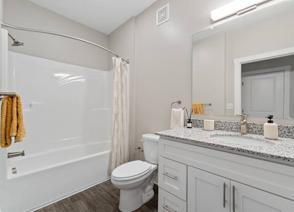 A white toilet sits in a bathroom with a marble counter top.