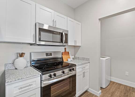 A kitchen with white cabinets and a stove top oven.