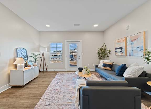 A living room with a grey couch, a patterned rug, and a painting on the wall.