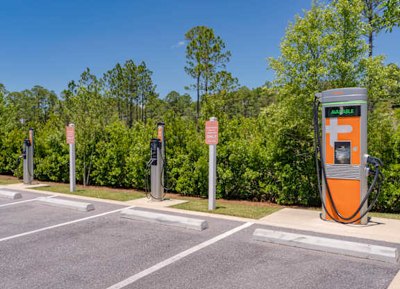 A row of electric vehicle charging stations are lined up in a parking lot.