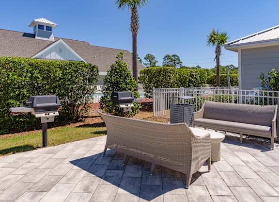 A patio with a white couch and a table with a plant on it.