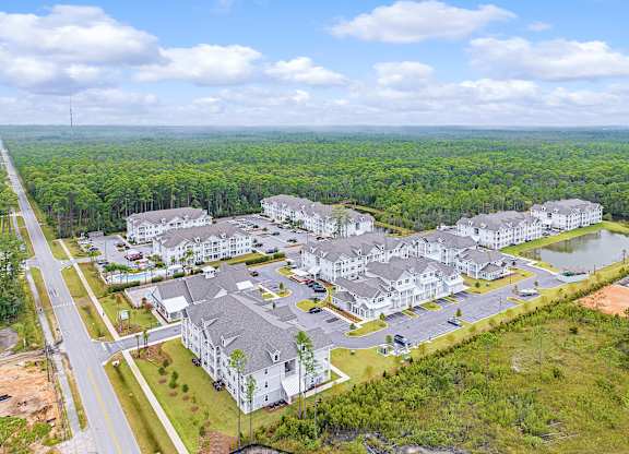 A bird's eye view of a large residential complex surrounded by a forest.