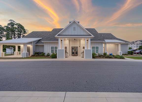 A white house with a grey roof and a sunset in the background.
