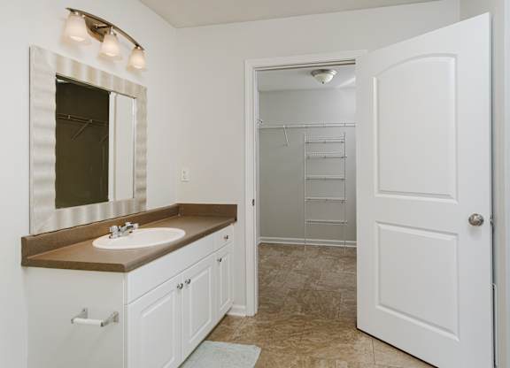 A bathroom with a sink, mirror, and white cabinetry.