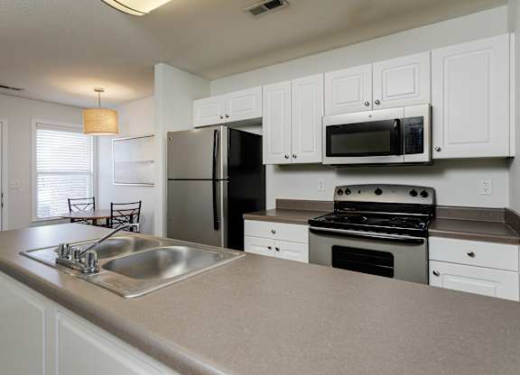A kitchen with white cabinets and a black refrigerator.