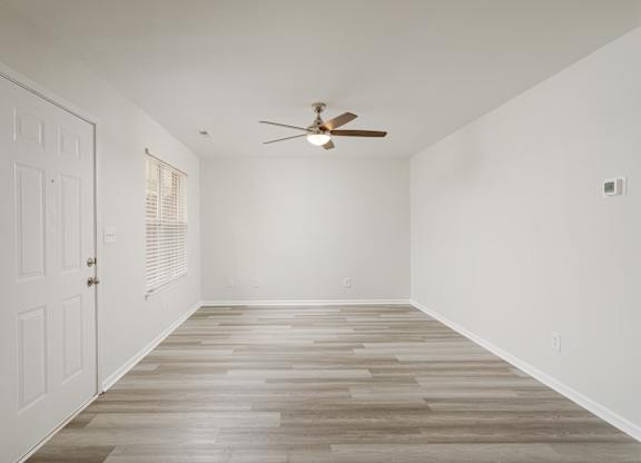 A room with a white door and a ceiling fan.