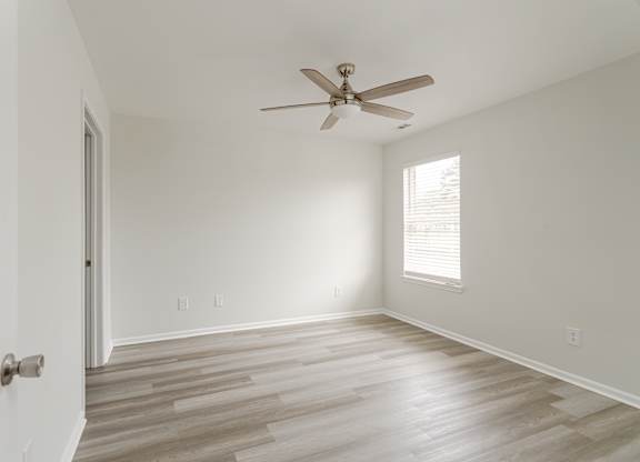 A room with a ceiling fan and wooden flooring.