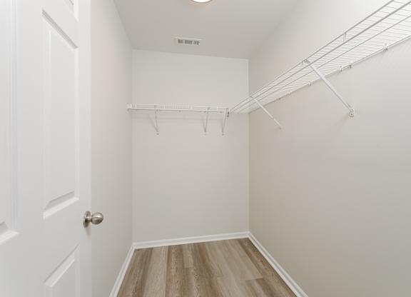 A white closet with a door and a shelf.