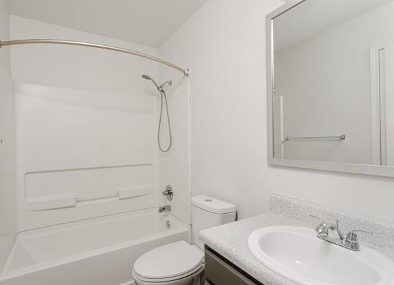 A white bathroom with a toilet, sink, and shower.