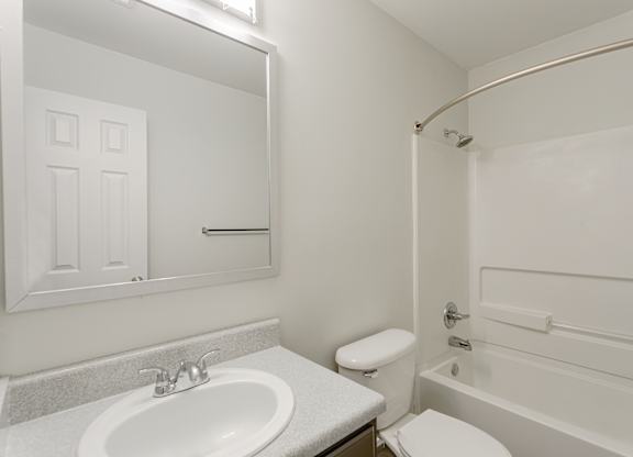A white bathroom with a sink, toilet, and bathtub.
