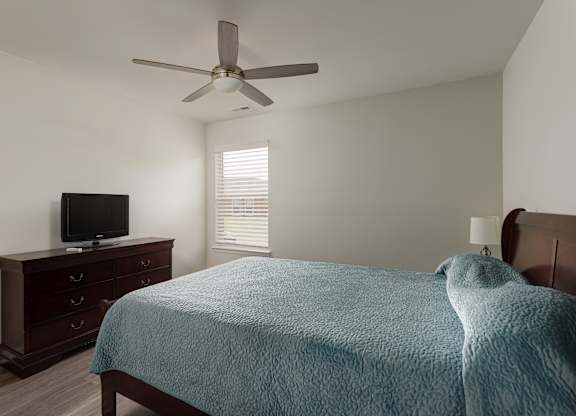 A bedroom with a bed, dresser, and television.