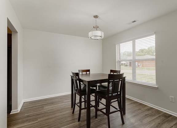 A dining room with a wooden table and chairs.