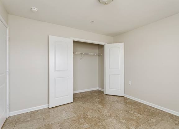 A room with a tiled floor and a closet with a white door.