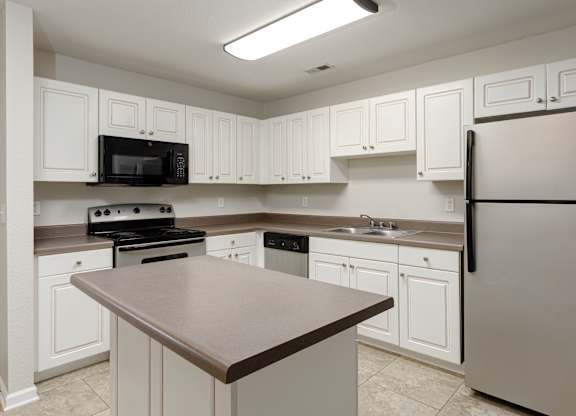 A kitchen with white cabinets and a black countertop.