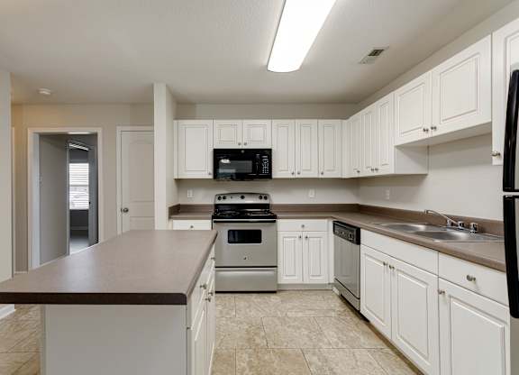 A kitchen with white cabinets and a black refrigerator.