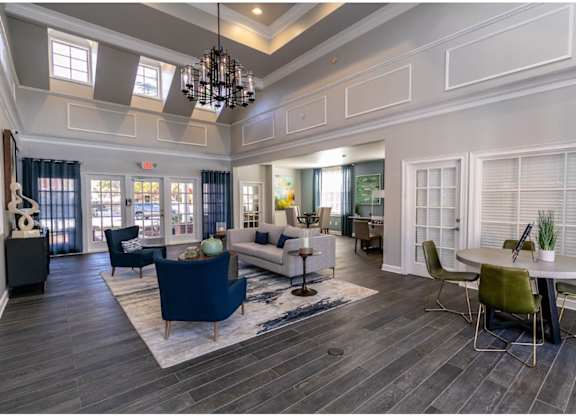 A spacious living room with a dark blue sofa and a chandelier.