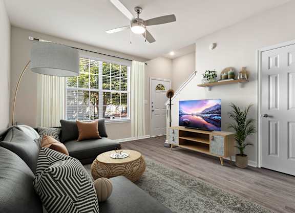 A living room with a grey couch and a television on a wooden stand.