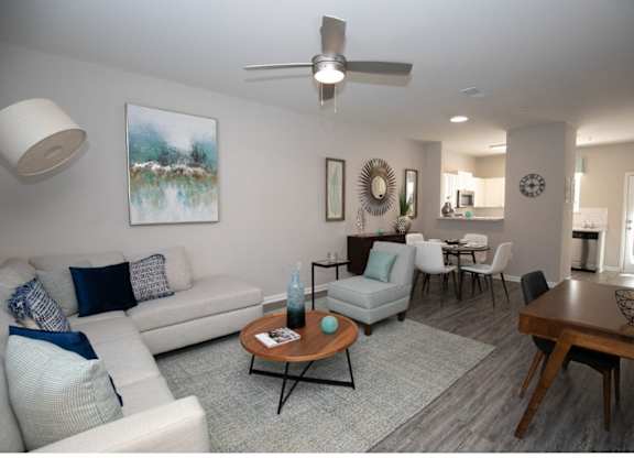 A living room with a white couch, a coffee table, and a painting on the wall.