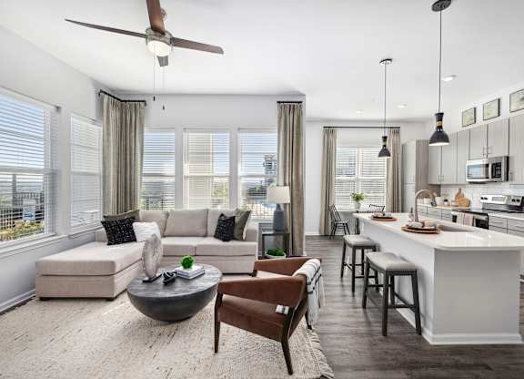 A modern kitchen and living room with a ceiling fan and a dining table.
