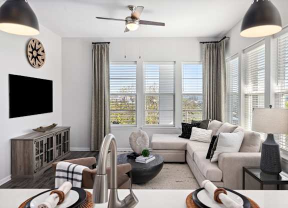 A living room with a large couch, a television, and a ceiling fan.