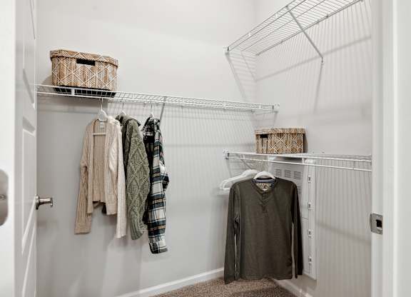 A white closet with clothes hanging on a wire rack.