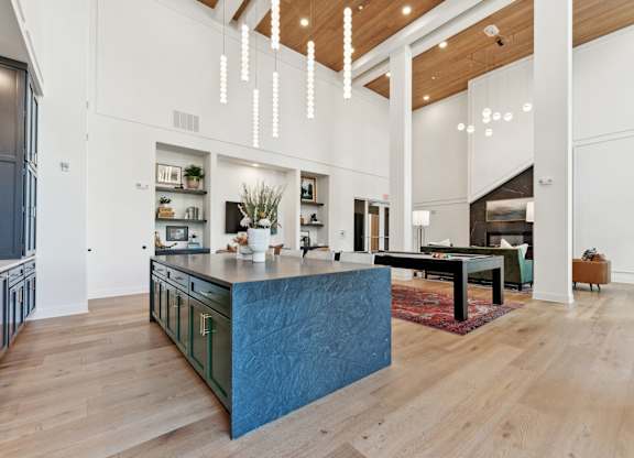 a large kitchen with a blue island and a living room with a pool table