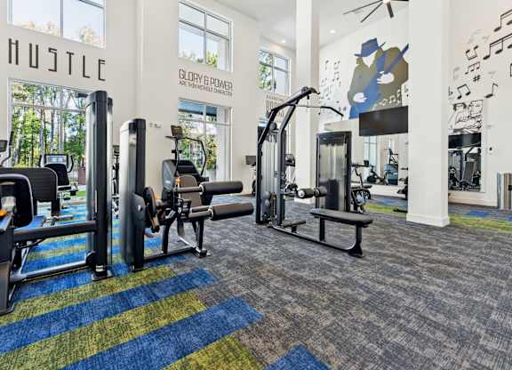 a gym with weights and cardio equipment in a building with large windows