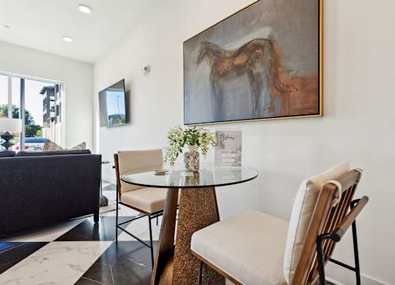 a dining room with a table and chairs and a painting on the wall