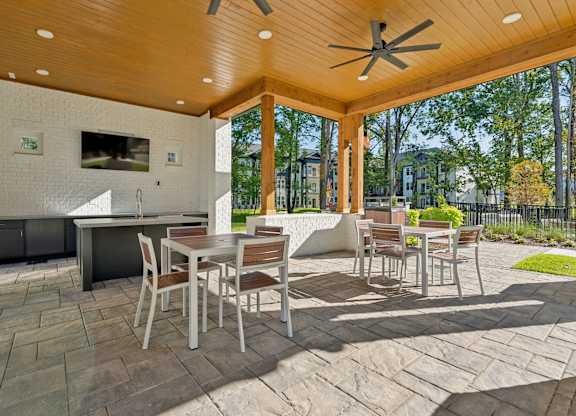 a covered patio with tables and chairs and a tv