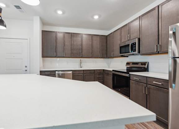 a kitchen with a large white counter top and wooden cabinets