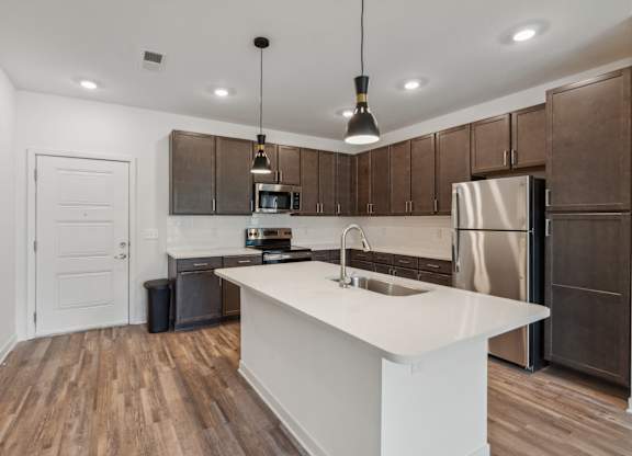 an open kitchen with a large white island and stainless steel appliances