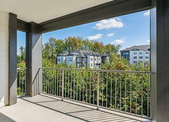 a balcony with a view of trees and houses in the distance