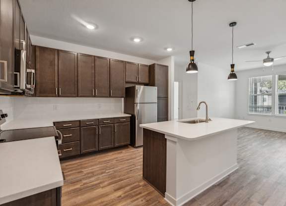 an open kitchen with a white counter top and wooden cabinets