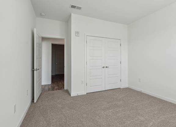 an empty bedroom with a closet and a door to a hallway