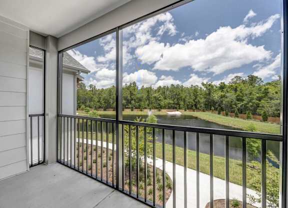 A balcony with a view of a green landscape and a blue sky with clouds.