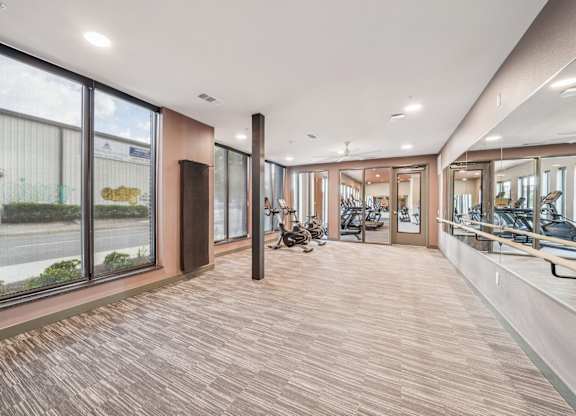 A spacious room with wooden flooring and large windows.