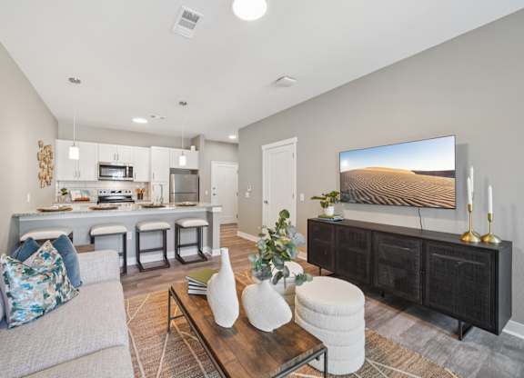 A modern living room with a grey couch, a coffee table, and a large painting on the wall.