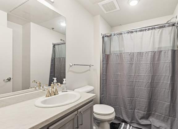 A bathroom with a sink, toilet, and shower curtain at The Tower Apartments, Alabama, 35401