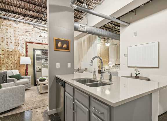 A modern kitchen with a large island and a couch in the living room at The Tower Apartments, Alabama