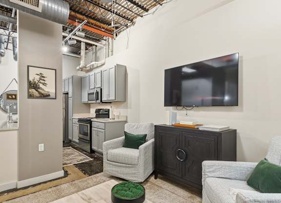 A living room with a television and a chair at The Tower Apartments, Alabama, 35401