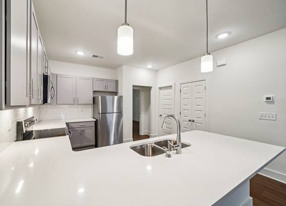 A modern kitchen with a white countertop and stainless steel appliances.