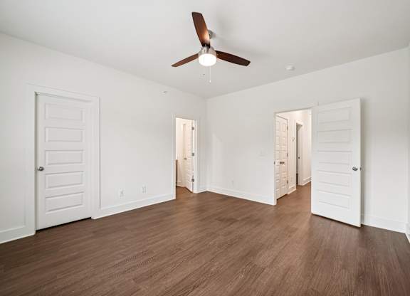 A room with a ceiling fan and wooden floors.