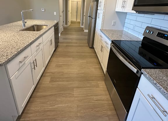 A kitchen with white cabinets and a black stove top oven at The Fitzroy Apartments in Birmingham, AL.