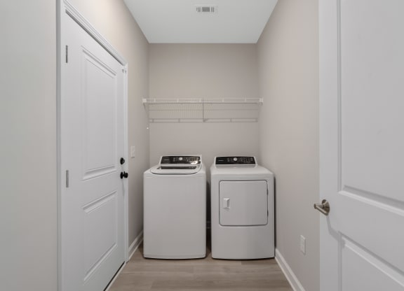 an empty laundry room with two washes and a dryer at The Cottages at Foley Farms apartments in Foley, AL
