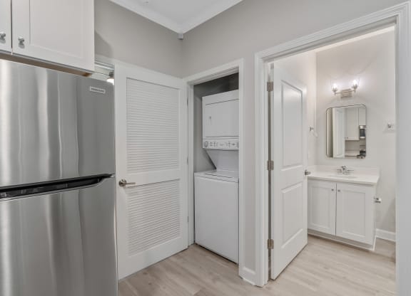 a kitchen with a refrigerator and a sink and a door to a closet at The Cottages at Foley Farms apartments in Foley, AL